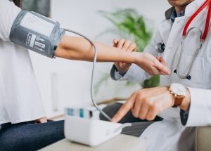 Young male psysician with patient measuring blood pressure